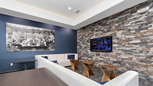 A modern lounge area with a stone wall, a large black and white photo, and a flat-screen TV.