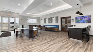 A modern interior with a bar area, seating, and a TV screen displaying a sports event.