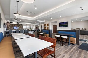 A modern restaurant with white tables, brown cushioned benches, and a stone wall backdrop. - Holiday Inn Express Kansas City North Parkville (Parkville)