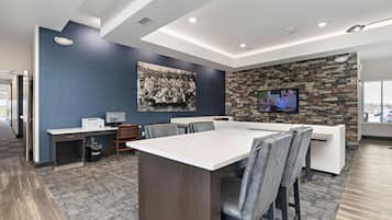 A modern conference room with a large table, chairs, a computer, and a television.