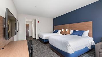Habitación de hotel con dos camas, un escritorio y una televisión.