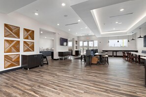 A spacious, modern interior with a wooden floor, a kitchen area, and a dining space with tables and chairs. - Holiday Inn Express Kansas City North Parkville (Parkville)
