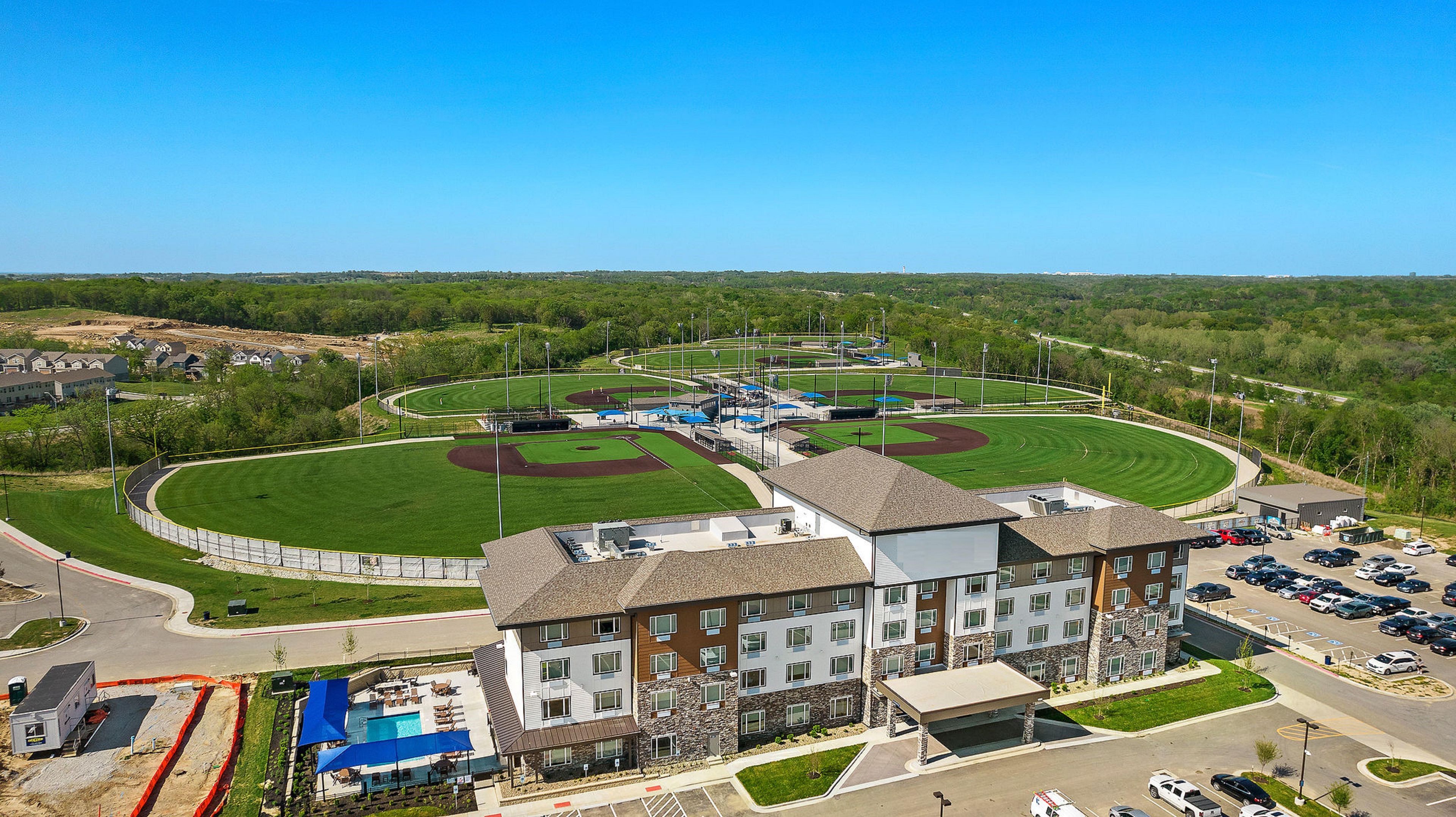 A multi-story hotel with a swimming pool and a baseball field.