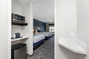 A hotel room with two beds, a microwave, a mini fridge, and a white shelf. - Holiday Inn Express Kansas City North Parkville (Parkville)