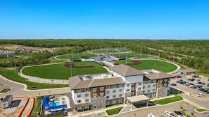A multi-story hotel with a swimming pool and a baseball field.