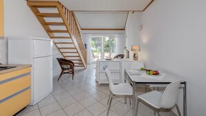 A kitchen with a refrigerator, a dining table with chairs, a staircase, and a view of the outdoors. - Beachfront apartment with balcony and parking (Split)