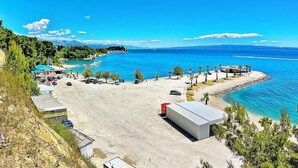 A coastal area with a parking lot, buildings, and a clear view of the sea. - Beachfront apartment with balcony and parking (Split)