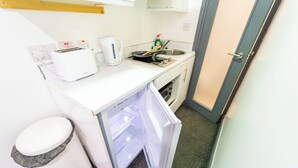 A compact kitchen with a white countertop, a toaster, a kettle, a frying pan, and a sink. - Beautiful 1-Bed Studio in Birmingham (Birmingham)