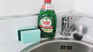 A kitchen sink with a green Fairy Platinum Quickwash bottle, a blue sponge, and a black soap bar. - Beautiful 1-Bed Studio in Birmingham (Birmingham)