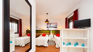 Ein Hotelzimmer mit zwei Betten, einem Fernseher, einem Regal mit Gläsern und einem Gemälde an der Wand.
