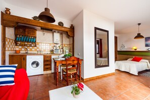 Un espace de vie compact comprenant une cuisine, un coin repas et un lit.