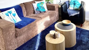 A living room with a brown sofa, a blue rug, a wooden coffee table, and a black armchair. - 🔆PINEPLACE🔆BFast,Wi-Fi,Walk2Pizza,Coffee,Liquor (Norlane)