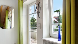 Een kamer met een groot raam, een radiator en een blauwe vaas op de vensterbank.