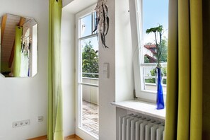 Una habitación con un ventanal grande, un radiador y un florero azul en el alféizar.