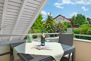A balcony with a table set for two, a bottle of wine, and two glasses.