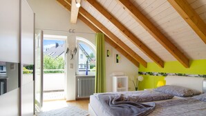 Een slaapkamer met een bed, een radiator, een raam en uitzicht op het omliggende landschap.