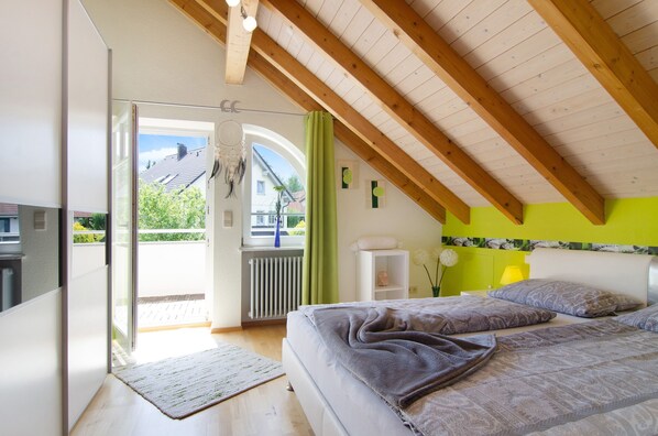 A bedroom with a bed, a radiator, a window, and a view of the outside.