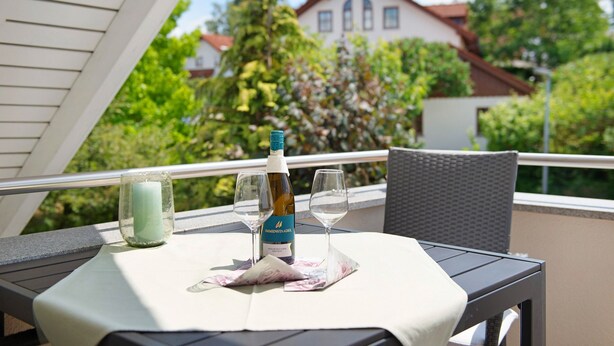 Een balkon met een tafel, een fles wijn en twee glazen.