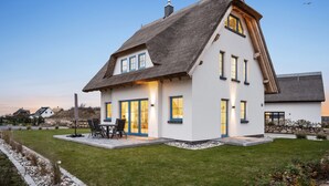 A house with a steeply pitched roof, large windows, and a well-maintained lawn. - Holiday Home 'Ankerplatz' with Sea View, Sauna, and Gas Fireplace (Dranske)