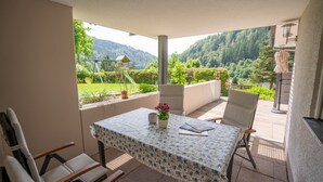A patio with a table, chairs, and a view of a lush garden and mountains. - Holiday Apartment "Haus Franziska" with Mountain View, Private Terrace & Wi-Fi (Todtnau /Brandenberg)