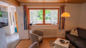 A cozy living room with a sofa, armchair, and a small table with a bowl and remote control. - Holiday Apartment "Haus Franziska" with Mountain View, Private Terrace & Wi-Fi (Todtnau /Brandenberg)