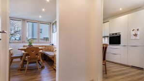 Una cocina moderna con piso de madera, armarios blancos y horno empotrado.
