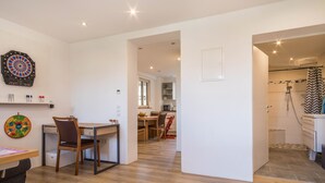 Un interior moderno con dardos, un escritorio con silla, un comedor con mesa y sillas, y una zona de ducha.