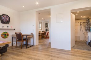 Un interior moderno con dardos, un escritorio con silla, un comedor con mesa y sillas, y una zona de ducha.