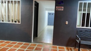 A hallway with a tiled floor, a door leading to another room, and a sign indicating the establishment is smoke-free.