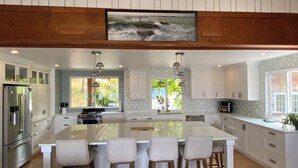A modern kitchen with a large island, white cabinetry, and a view of the outdoors. - Family adventures await in this ocean front house!  (Pet friendly!)
 (Quathiaski Cove)
