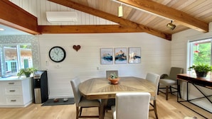 A modern kitchen with white cabinets, a wooden dining table, and a clock on the wall. - Family adventures await in this ocean front house!  (Pet friendly!)
 (Quathiaski Cove)