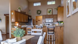 A kitchen with wooden cabinets, a dining table with chairs, a refrigerator, and a microwave. - Waterfront lake house with your own private dock and amazing views.  (Eucha)