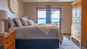 A bedroom with a large bed, wooden dresser, and a ceiling fan. - Waterfront lake house with your own private dock and amazing views.  (Eucha)