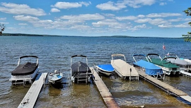 Un quai où sont amarrés plusieurs bateaux, un ciel dégagé et un lac paisible.