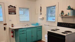 Une cuisine avec des armoires de couleur turquoise, un fourneau blanc et un plancher en bois.