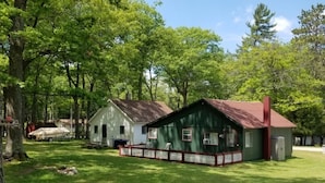 Un chalet rustique avec un toit rouge, entouré d’arbres verdoyants et doté d’une cour clôturée.