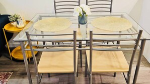 Une table à manger avec quatre chaises, un vase rempli de fleurs et un plateau avec une théière et un sucrier.