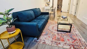 Un salon moderne avec un canapé bleu, une table basse en verre et un tapis à motifs.