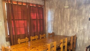 Comedor con mesa y sillas de madera, un sofá y cortinas.