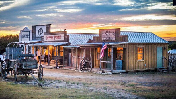 Un edificio rústico con un letrero que indica 'Copper Penny Trading Post' y 'Bank'.