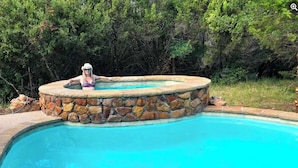 Una piscina con un muro de piedra y una persona de pie sobre él.