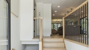 A modern staircase with wooden steps and a glass door on the left.