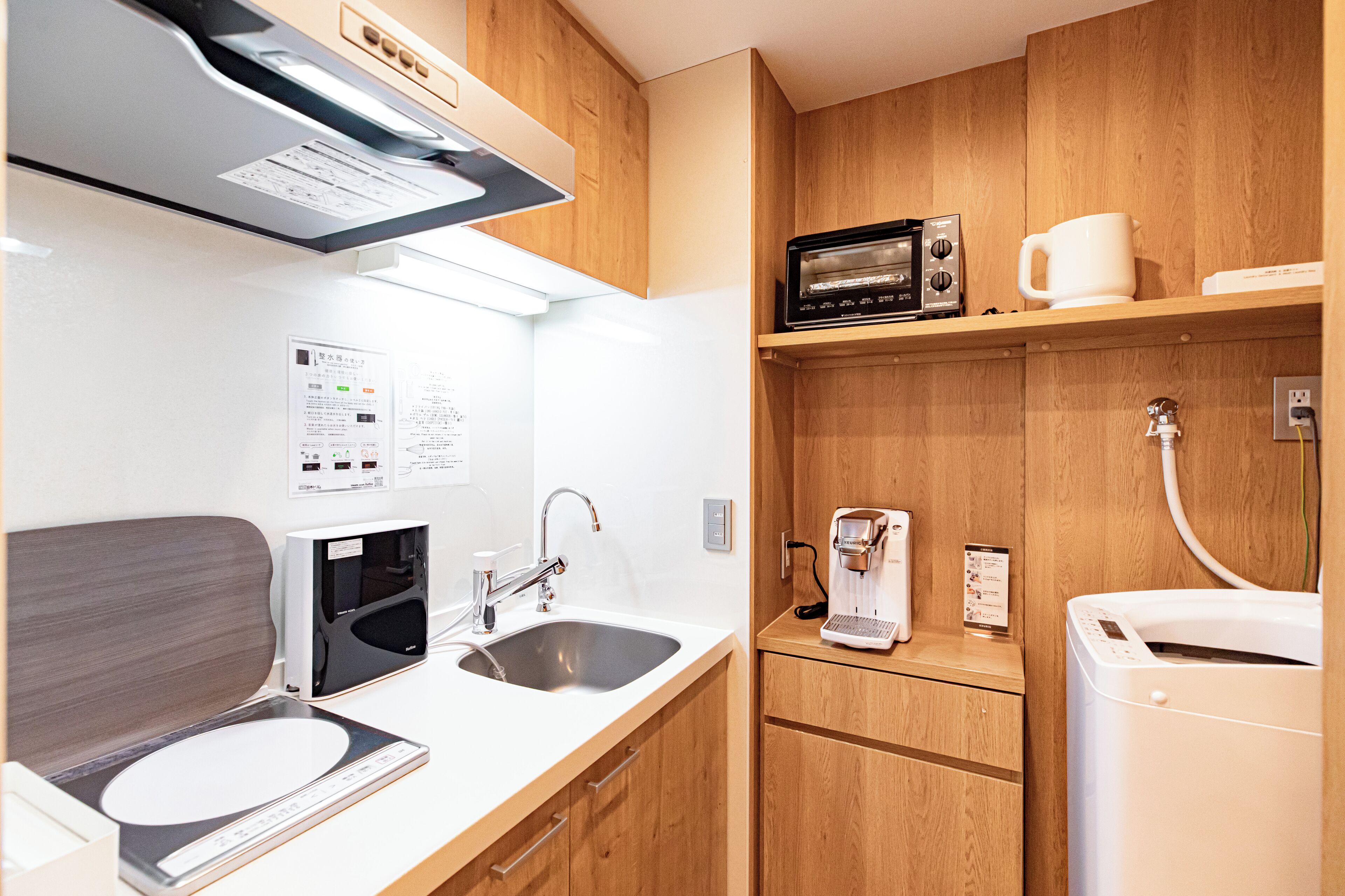 A compact kitchen with a sink, a microwave, a coffee maker, and a dishwasher.