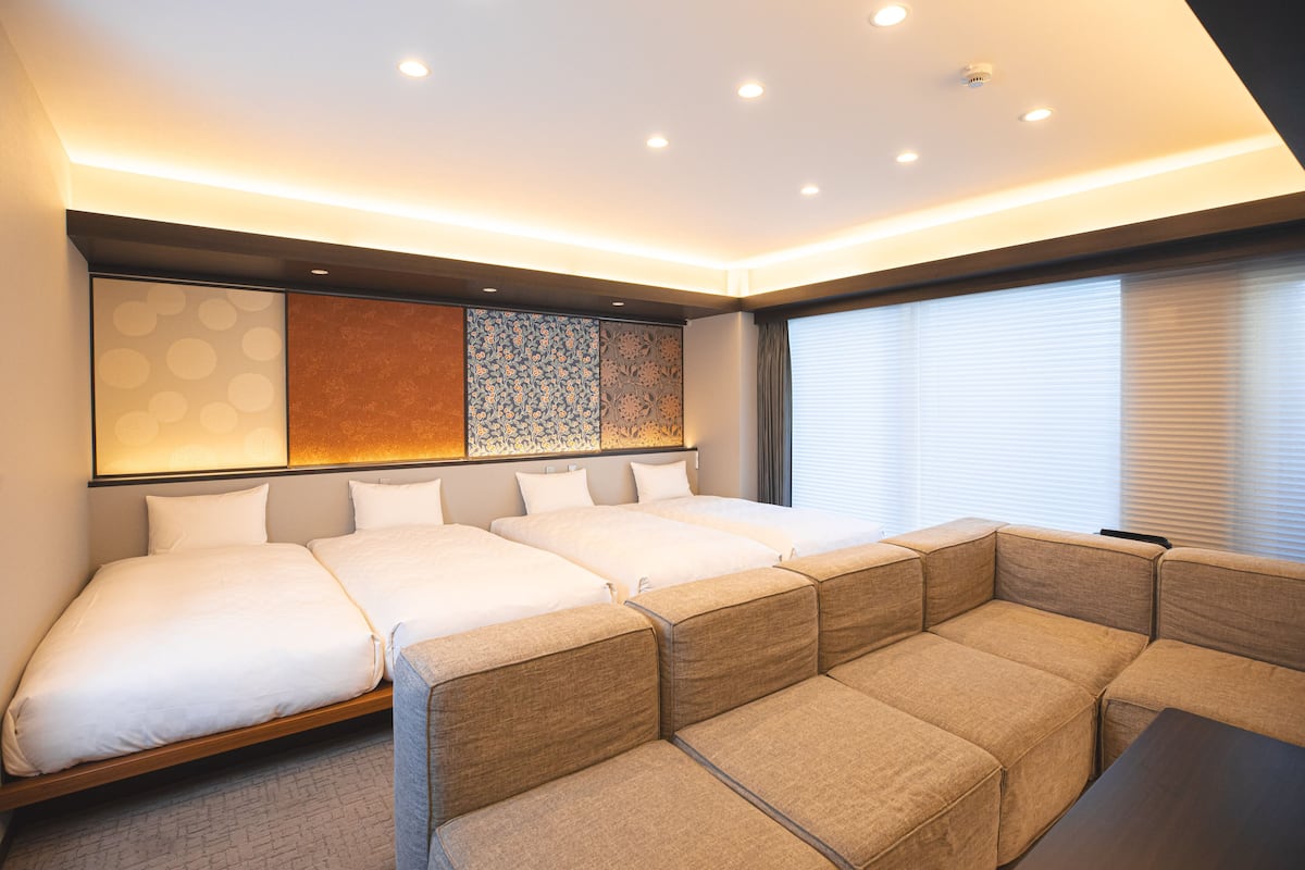 A modern hotel room with a large bed, a sofa, and a decorative wall.