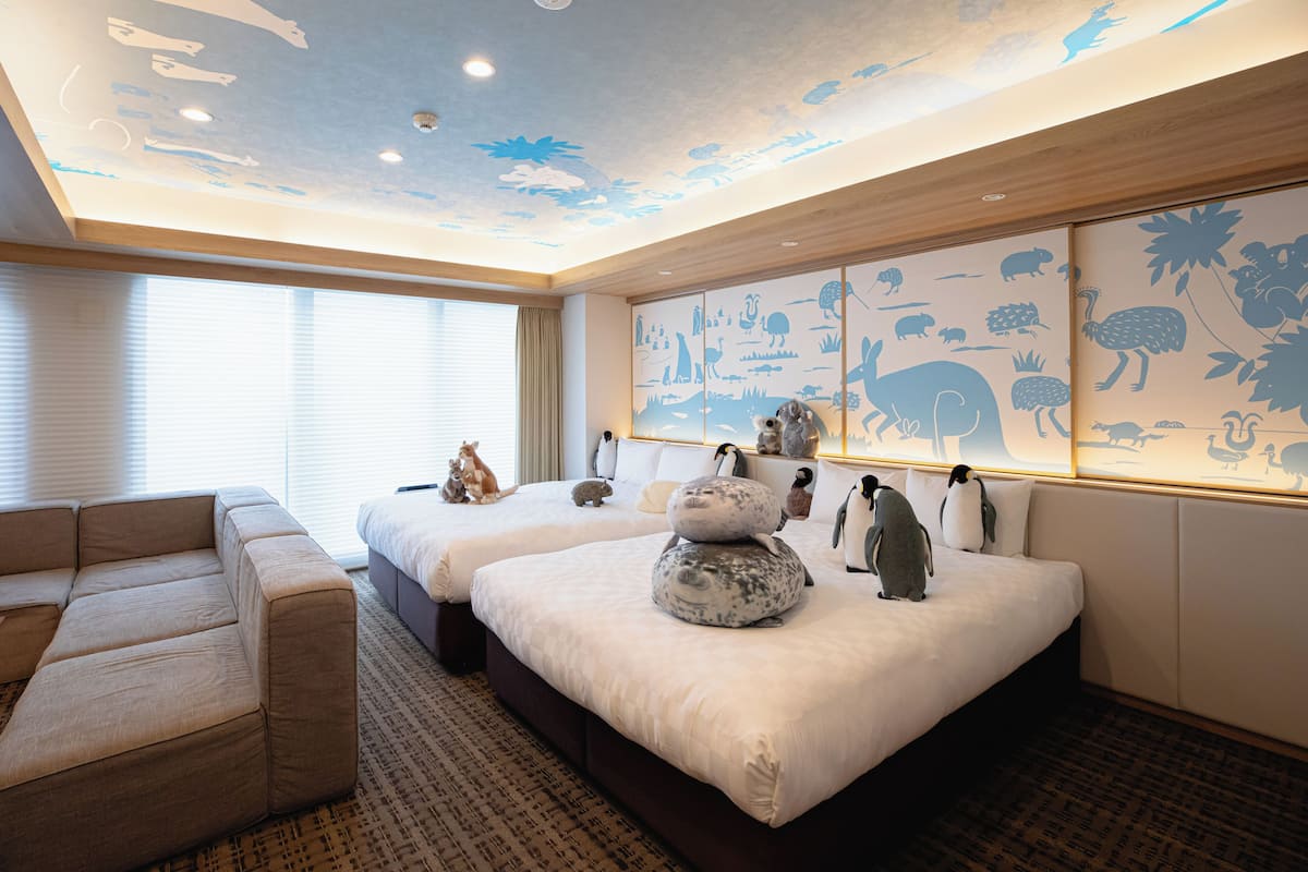 A hotel room with two beds, a sofa, and a wall with animal silhouettes.