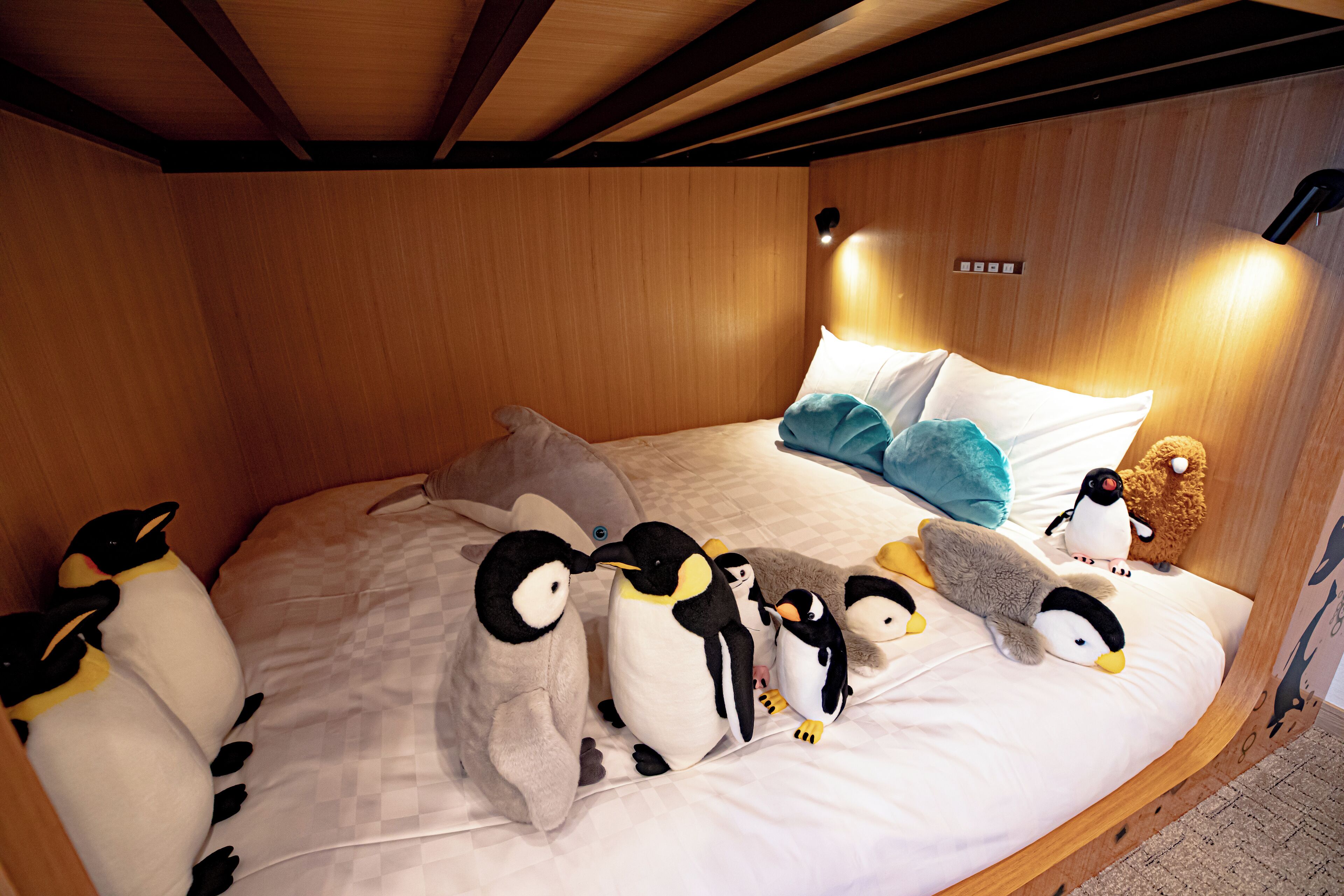 A bed with plush penguin toys and a teddy bear.