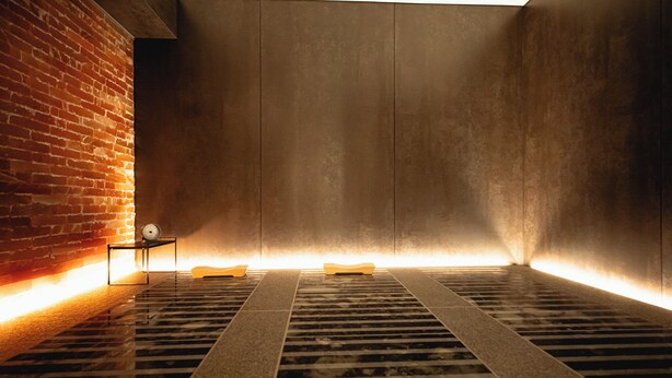 Un intérieur moderne avec un mur en briques, un banc en métal et un sol à motifs.