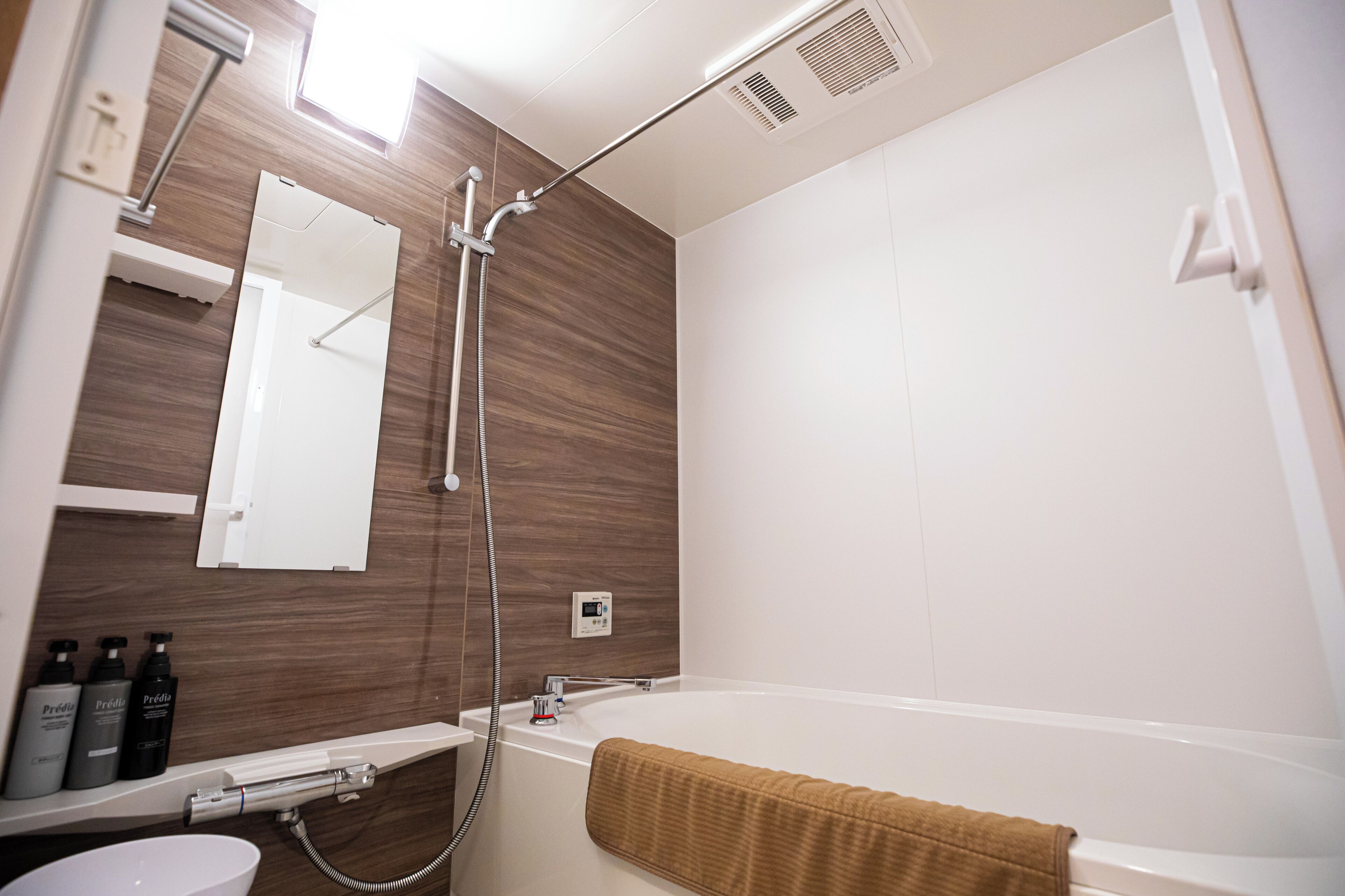A modern bathroom with a shower, a bathtub, a mirror, and a shelf with toiletries.