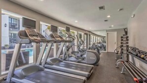 Et fitnesscenter med løbebånd, crosstrainere og vægte.