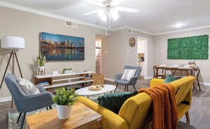 Een moderne woonkamer met een stadsgezicht schilderij, een eethoek en een groene wand.
